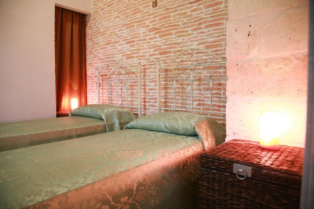Camera con letti in ferro battuto e muro in mattoni